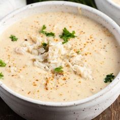 two white bowls filled with soup and garnished with parsley on the side