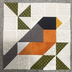 an orange and black patchwork piece is on the floor next to a gray surface