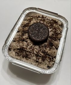 an oreo cookie sitting on top of some chocolate cake in a tin foil container