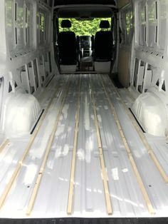 the interior of a white van with wood flooring and windows in place for storage