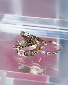 three wedding rings sitting on top of a pink table next to an empty plastic container