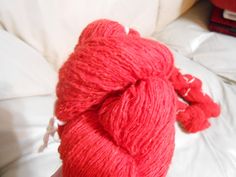 a red ball of yarn sitting on top of a bed