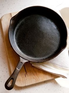 a cast iron skillet sitting on top of a cutting board next to a cloth