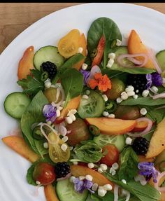 a white plate topped with lots of veggies and berries on top of it