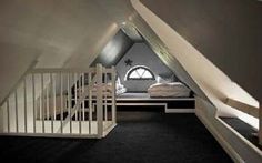 an attic bedroom with stairs leading up to the bed area and lofted room in the background