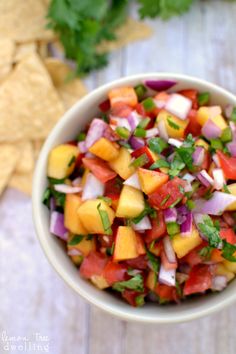 a bowl filled with fruit and veggies next to tortilla chips