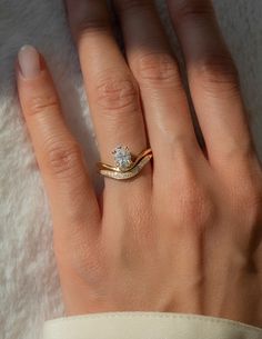 a woman's hand with a diamond ring on top of her finger and the other hand holding it