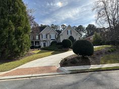 a large house on the corner of a street with trees and bushes in front of it