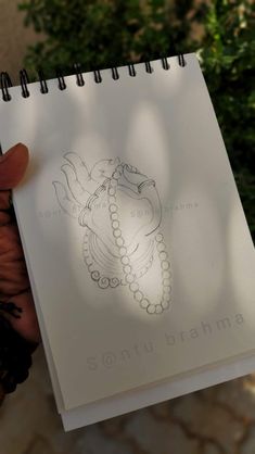 someone holding up a spiral notebook with a drawing on it