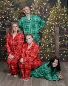 three women in matching pajamas posing for a photo together with christmas tree backdrop behind them