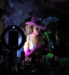 a woman wearing a pink cowboy hat in the dark