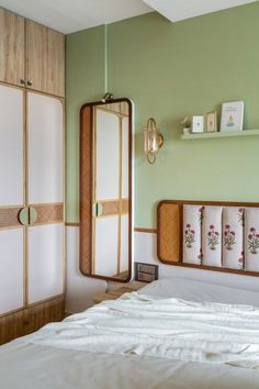 a bedroom with green walls and white linens on the bed in front of a mirror