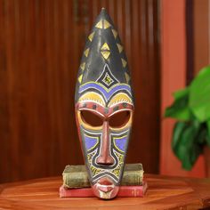 a mask sitting on top of a wooden table next to a potted green plant