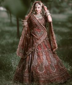 a woman in a red and gold wedding dress posing for the camera with her hands on her head