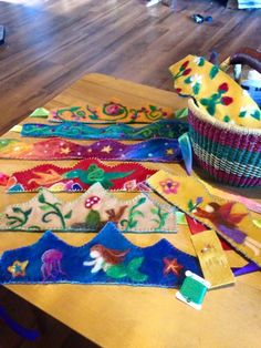 several pieces of colorful fabric sitting on top of a wooden table next to a basket