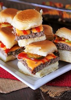 several hamburger sliders on a plate with ketchup and mustard in the middle