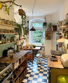 a kitchen with checkered flooring and lots of plants hanging from the ceiling over the stove