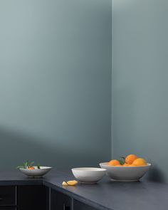 two bowls with oranges sit on a counter