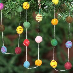 an ornament hanging from a christmas tree filled with colorful balls and yarns