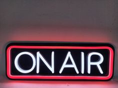 a neon sign that says on air in white letters and red trim around the edges