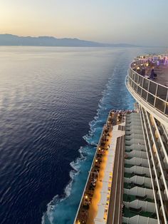 the top deck of a cruise ship looking down at the ocean and surrounding it is lit up with bright lights