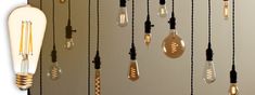 several light bulbs hanging from the ceiling in front of a wall with black cords and gold accents