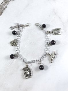 This Ares themed charm bracelet is the perfect accessory to showcase your love for the Greek myths in a subtle way.Charms included:SwordVultureSpartanBoarHelmet5 garnet beads are included between each charm.Comes in three sizes:Small: 6.5 inches (with extra rings at the end to expand up to 7.5 inches.)Standard: 7.5 inchesLarge: 8.5 inchesSecures with a lobster clasp. Bracelet and charms are lead and nickel free. Comes in a jewelry box so it would be ready to be given as a gift! Message me of you Symbolic Vintage Charm Bracelet For Gift, Symbolic Dangle Bracelets With Charms, Handmade Symbolic Charm Bracelet For Friendship, Symbolic Charms Bracelets For Gifts, Symbolic Bracelets With Dangling Charms, Symbolic Bracelets With Dangling Charms For Gifts, Spiritual Metal Charm Bracelet As Gift, Symbolic Bracelets With Dangling Charms As Gift, Spiritual Metal Charm Bracelet