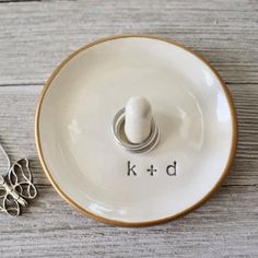 a white ceramic bowl with the word k - d on it next to some scissors