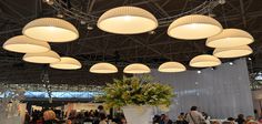 a group of people sitting at tables in a room with lights hanging from the ceiling