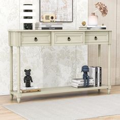 a white console table with two books on it and a teddy bear figurine next to it