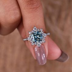 a woman's hand holding an engagement ring with blue and white diamonds on it