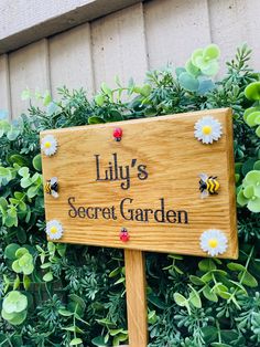 a wooden sign that says lily's secret garden in front of some green plants