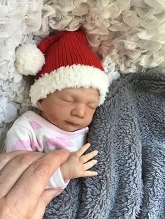 a baby wearing a santa hat laying on top of a blanket