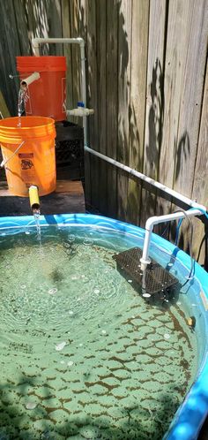 a large blue tub filled with water next to a wooden fence