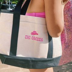 a woman carrying a tote bag with the word chi omega on it