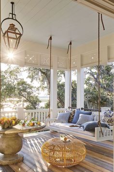 the porch is decorated with blue and white pillows, wicker furniture, and hanging chairs