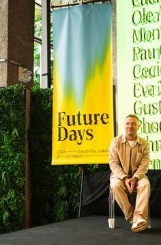 a man sitting on a chair in front of a banner