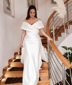 a woman in a white dress is walking down the stairs