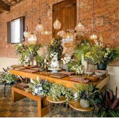 a long table with plants on it in front of a brick wall and wooden ceiling