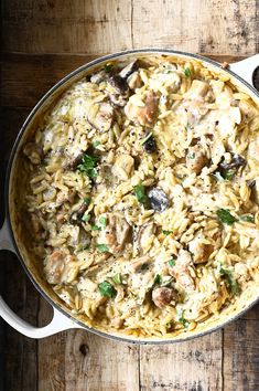 a pan filled with pasta and mushrooms on top of a wooden table