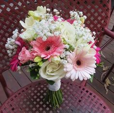 a bouquet of flowers sitting on top of a wooden table next to a red chair