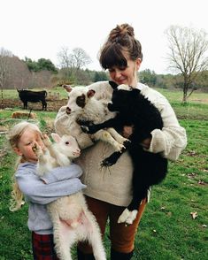 a woman holding two baby lambs in her arms