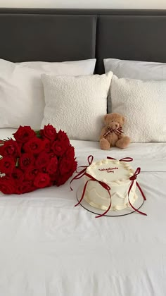 a bouquet of red roses sitting on top of a bed next to a teddy bear