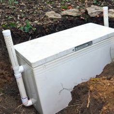 an old refrigerator sitting in the dirt next to a pile of dirt and some plants