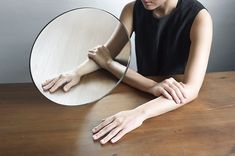 a woman sitting in front of a mirror on top of a wooden table