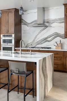 a large kitchen with marble counter tops and bar stools in front of the island