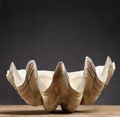 an animal sculpture sitting on top of a wooden table next to a vase with two large horns sticking out of it's sides