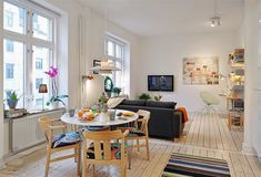 a living room filled with furniture and lots of windows next to a dining table in front of a tv