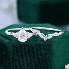 two engagement rings sitting on top of a green velvet box