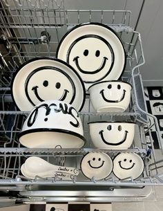 a dish rack filled with lots of white dishes covered in black smiley face plates and saucers